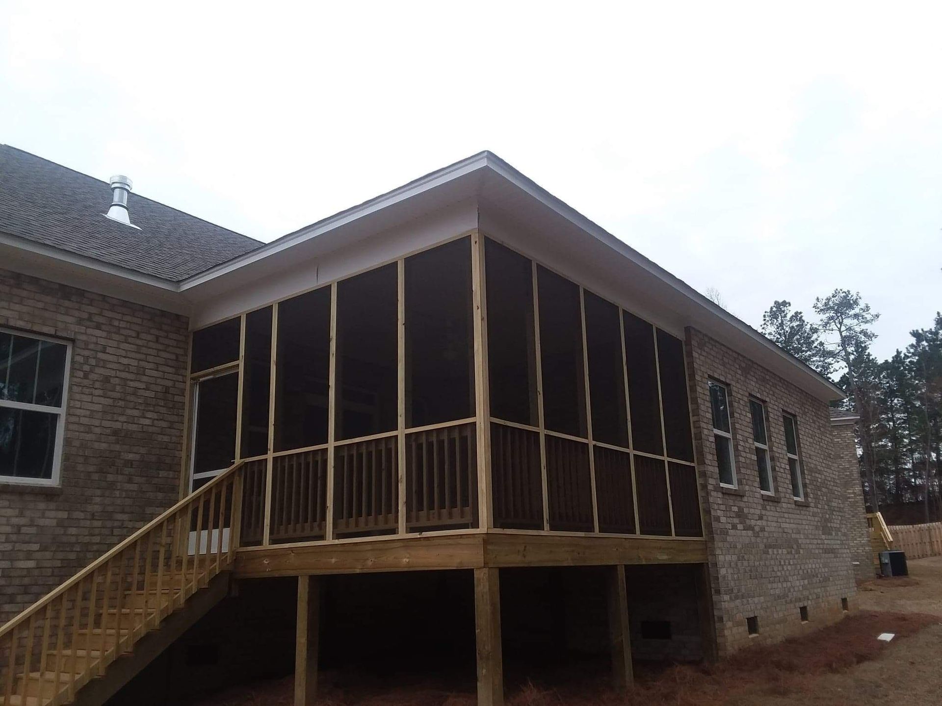 A screened in porch on the side of a brick house