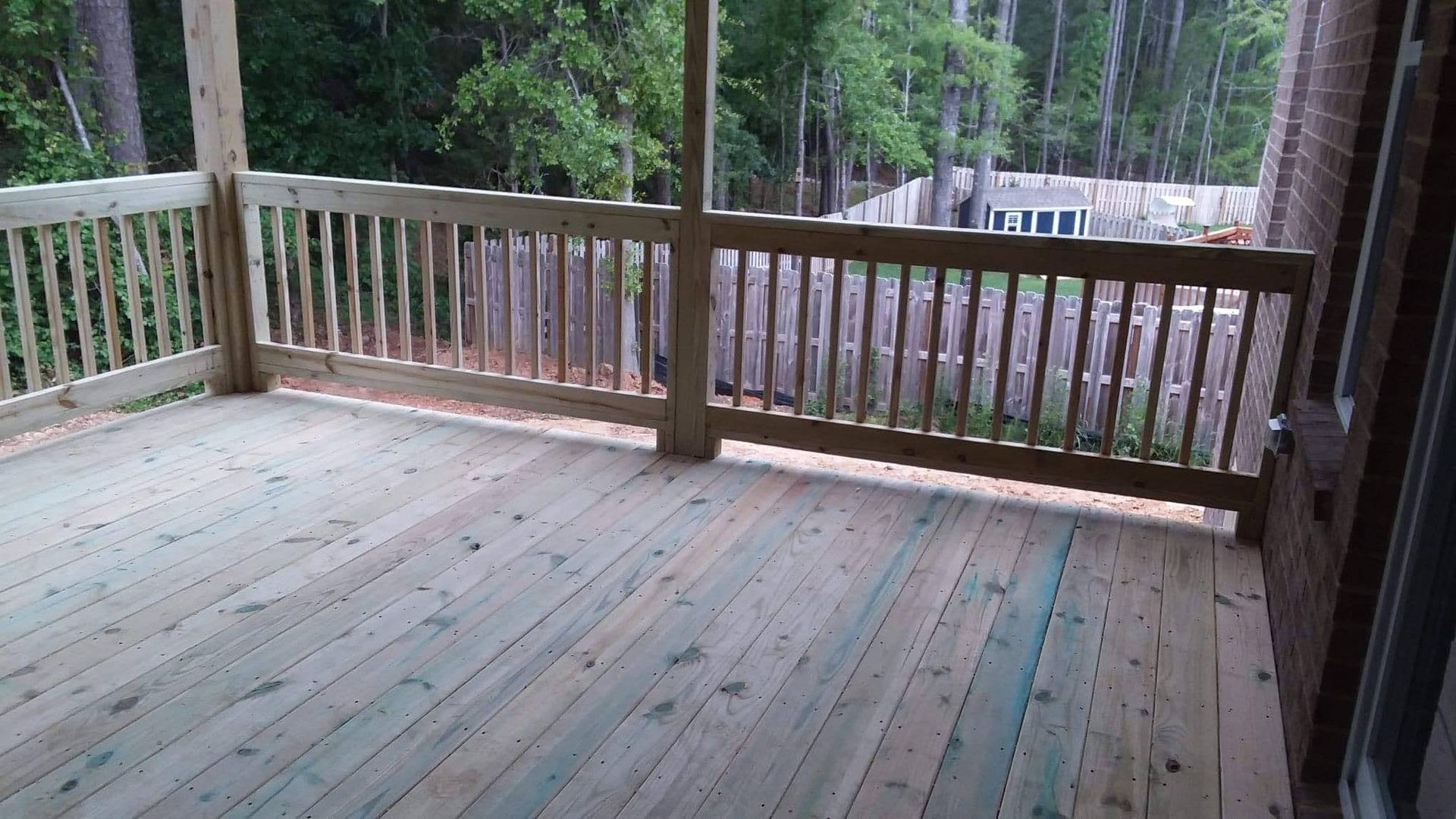 A wooden deck with a railing and trees in the background.