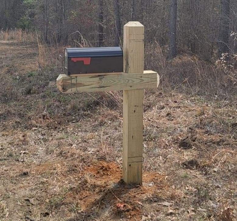A mailbox is attached to a wooden post in the shape of a cross