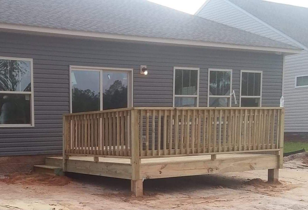 A wooden deck is sitting in front of a house.