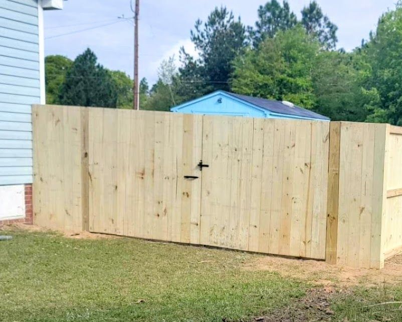 A wooden fence with a gate in the backyard of a house.