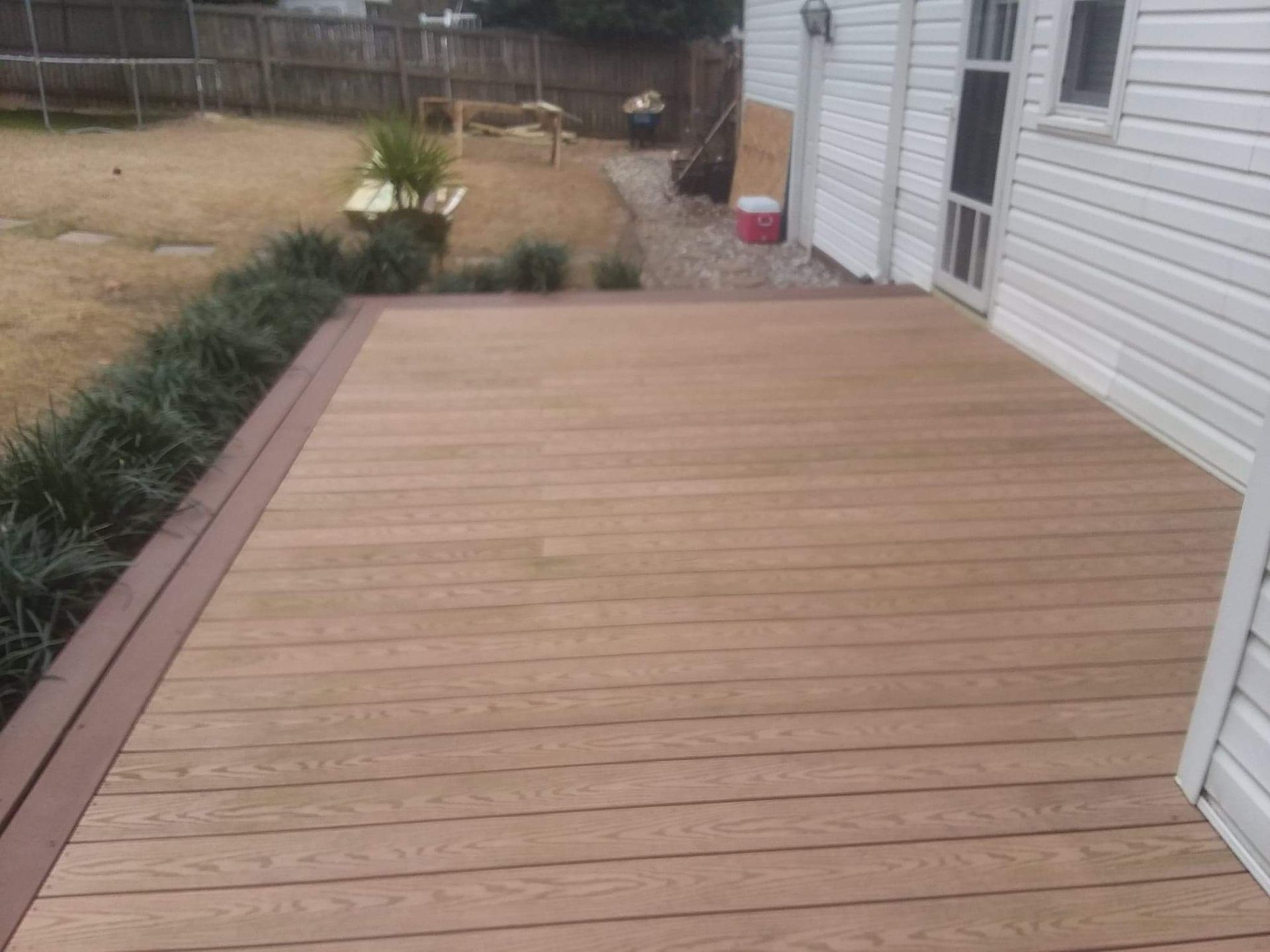 A wooden deck is sitting in front of a white house.