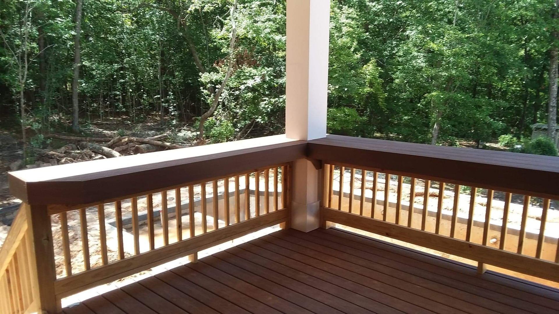 A wooden deck with a railing and trees in the background