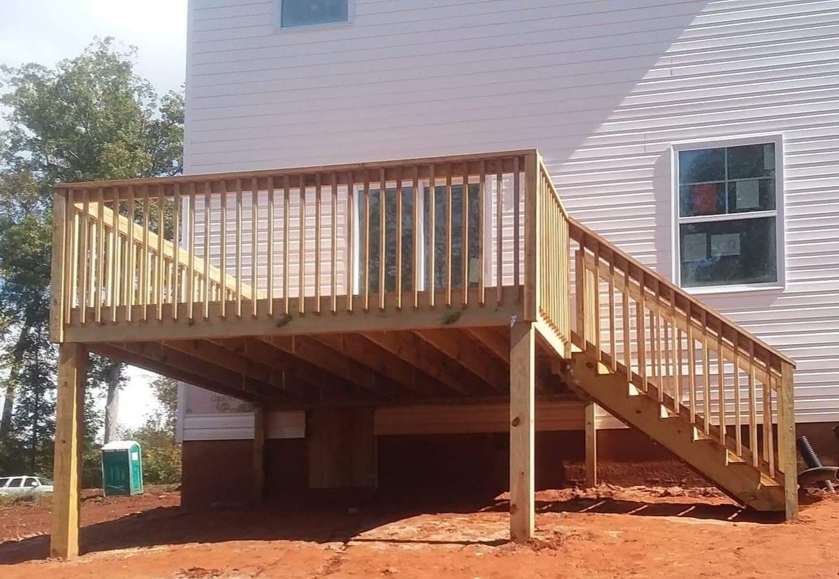 A white house with a wooden deck and stairs