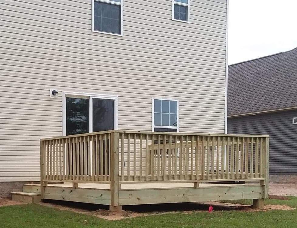 A large wooden deck is sitting in front of a house.