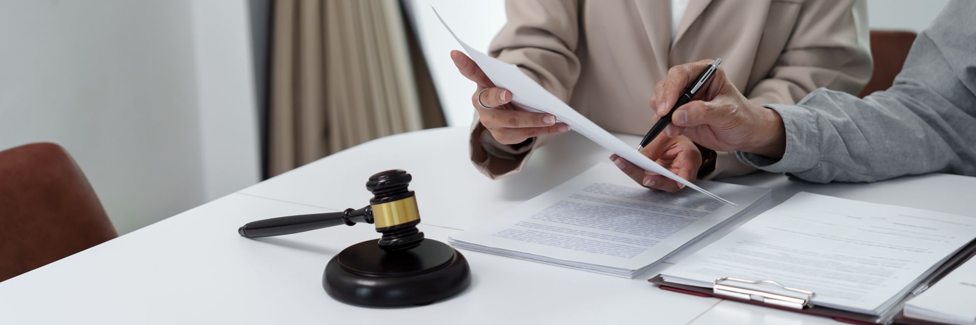 People reviewing documents at a table with a gavel. One person is pointing a pen at the document.