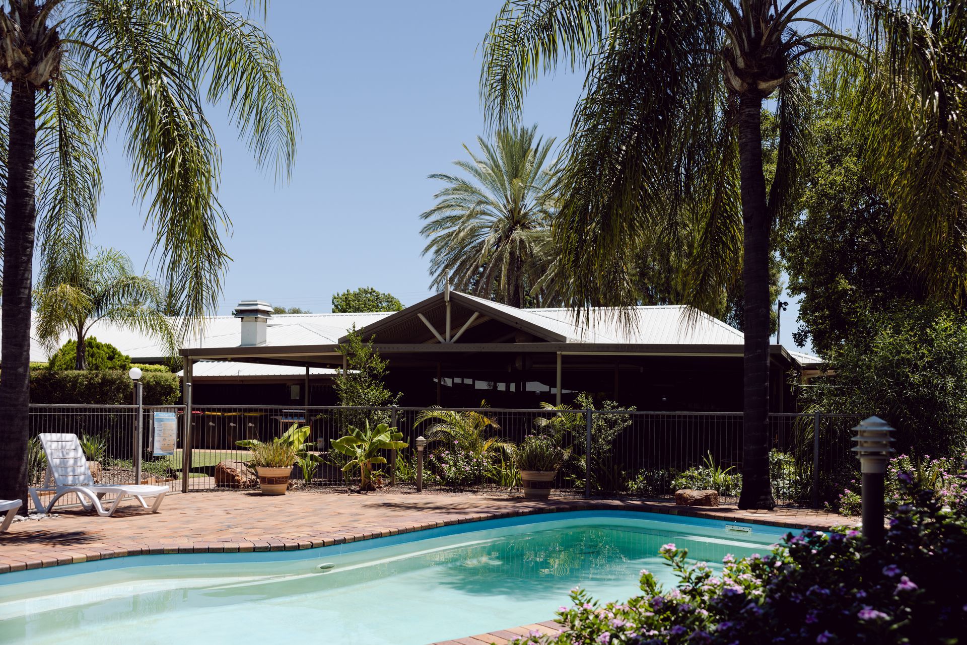 A large swimming pool in front of a house with palm trees