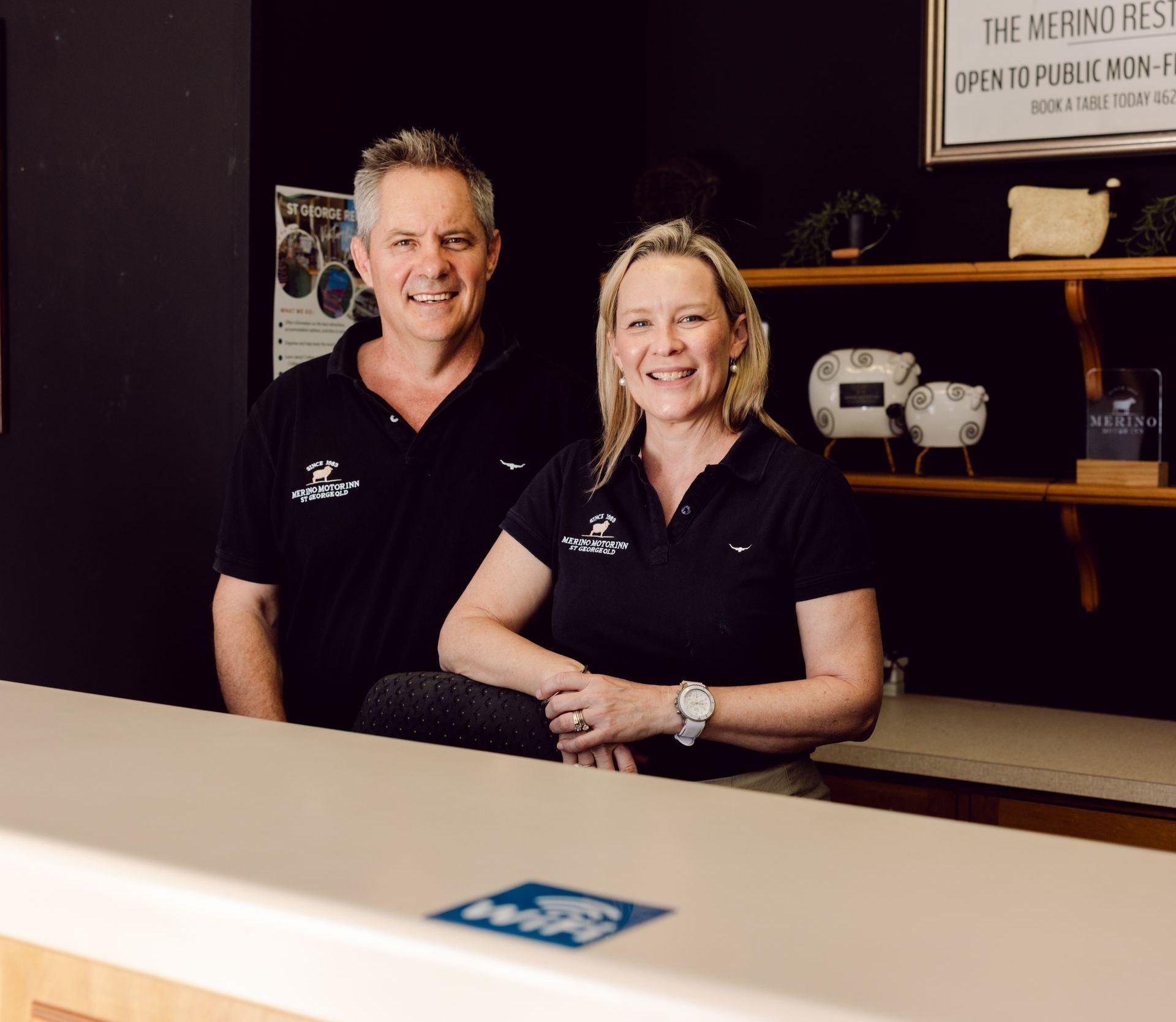 A man and a woman are standing behind a counter and smiling