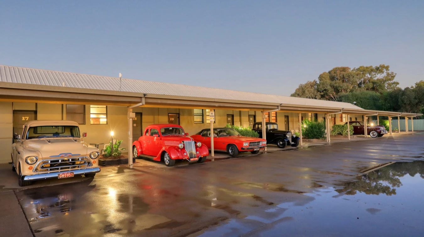 A row of old cars are parked in front of a building.