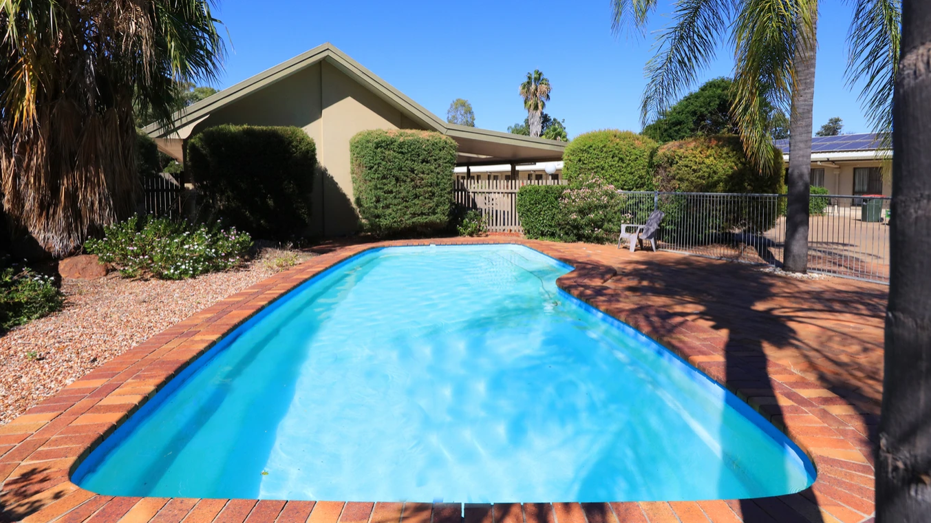 A large swimming pool with a house in the background