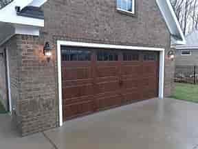 A large brown garage door is on the side of a brick building.