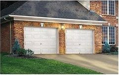 There are two garage doors in front of a brick house.