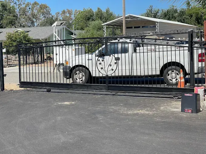 Black metal gate with white truck parked behind it.