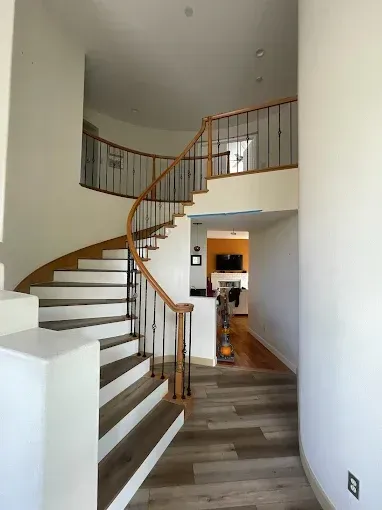 Curved staircase with wood and black metal railings, leading to a second floor.