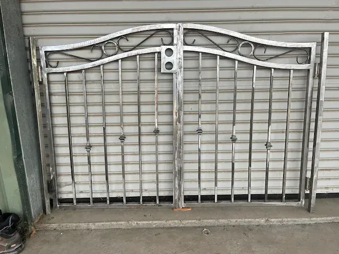 Metal gate with vertical bars and decorative scrollwork.