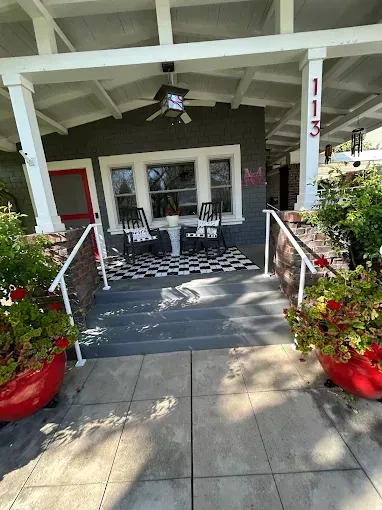 Gray home front porch with steps, a checkerboard rug, and two rocking chairs.
