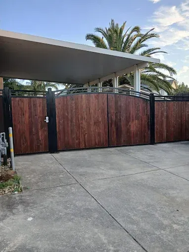 Wooden gate with black metal frame and carport.