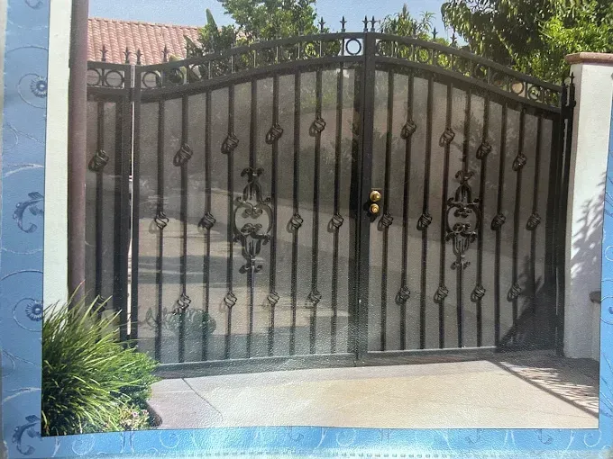 Black wrought iron driveway gates with decorative scrollwork.