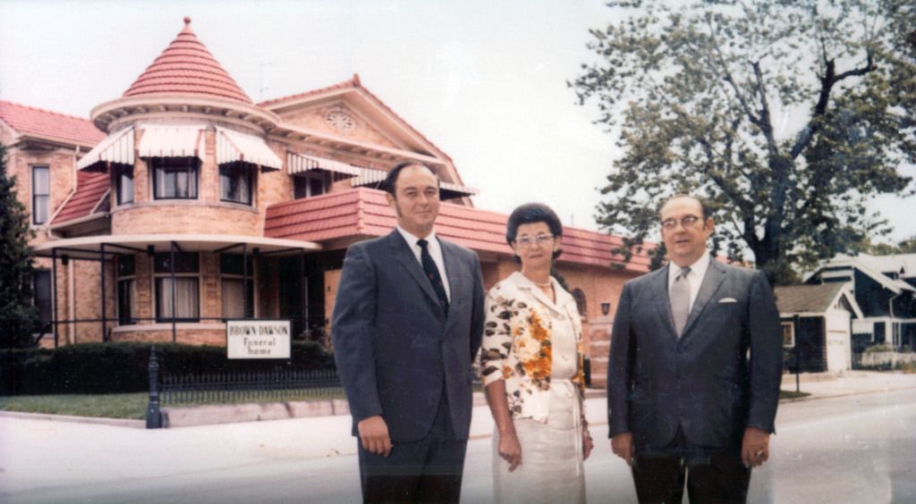 Three men and a woman are standing in front of a large house