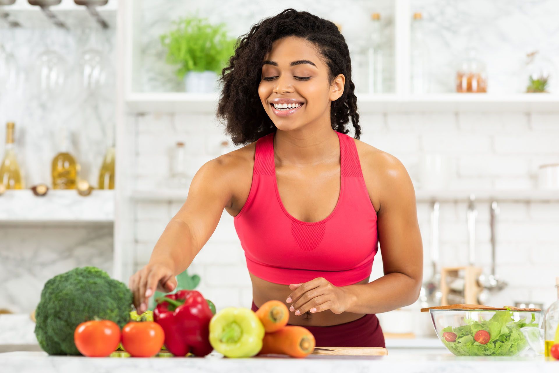 Woman in athletic wear preparing vegetables in a bright kitchen