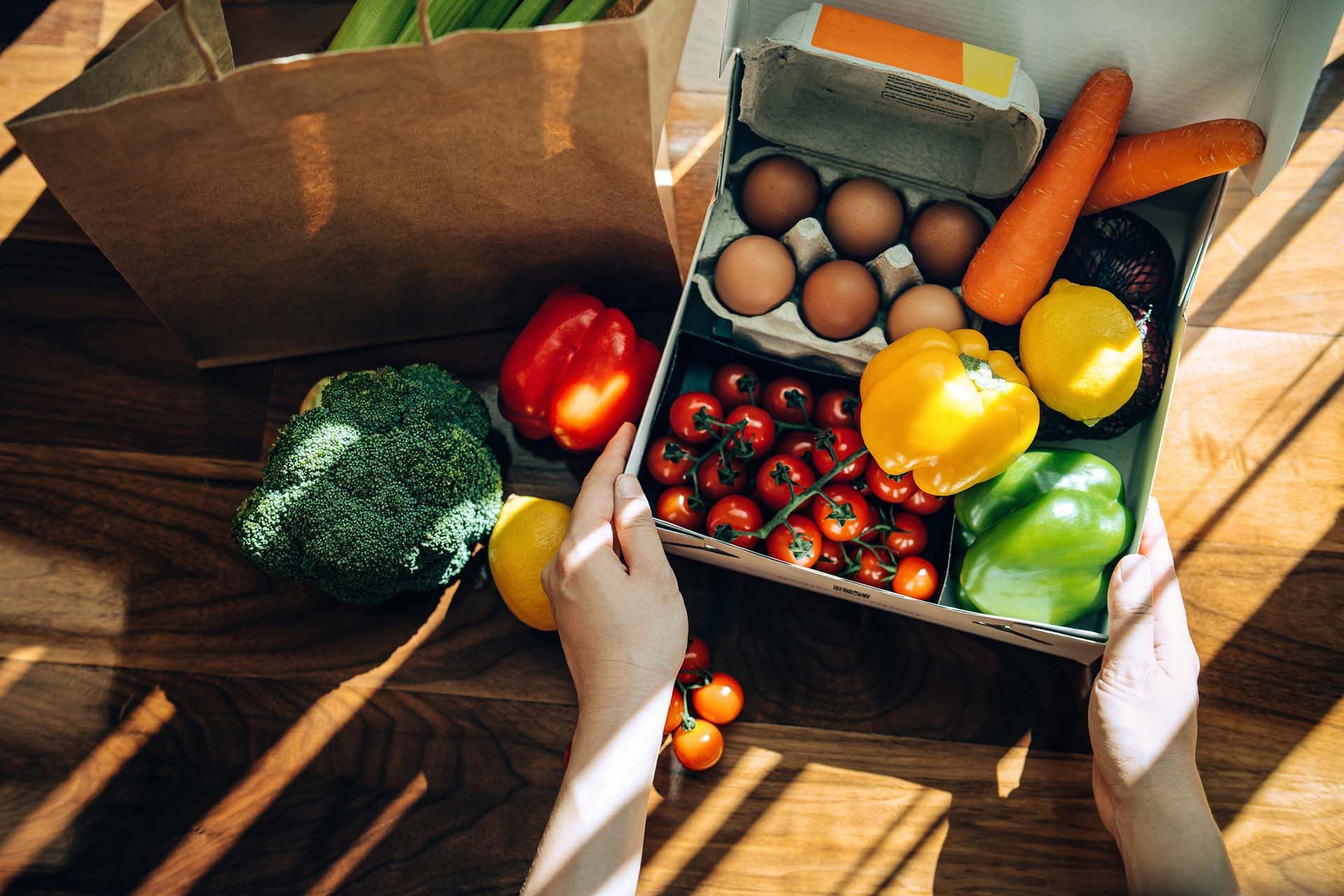 Hands holding a box of fresh groceries