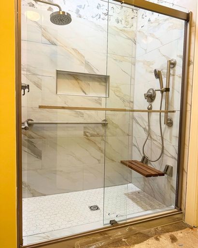 Modern glass shower with marble tile, gold trim, built-in niche, and handheld showerhead Modern glass shower with marble tile, gold trim, built-in niche, and handheld showerhead