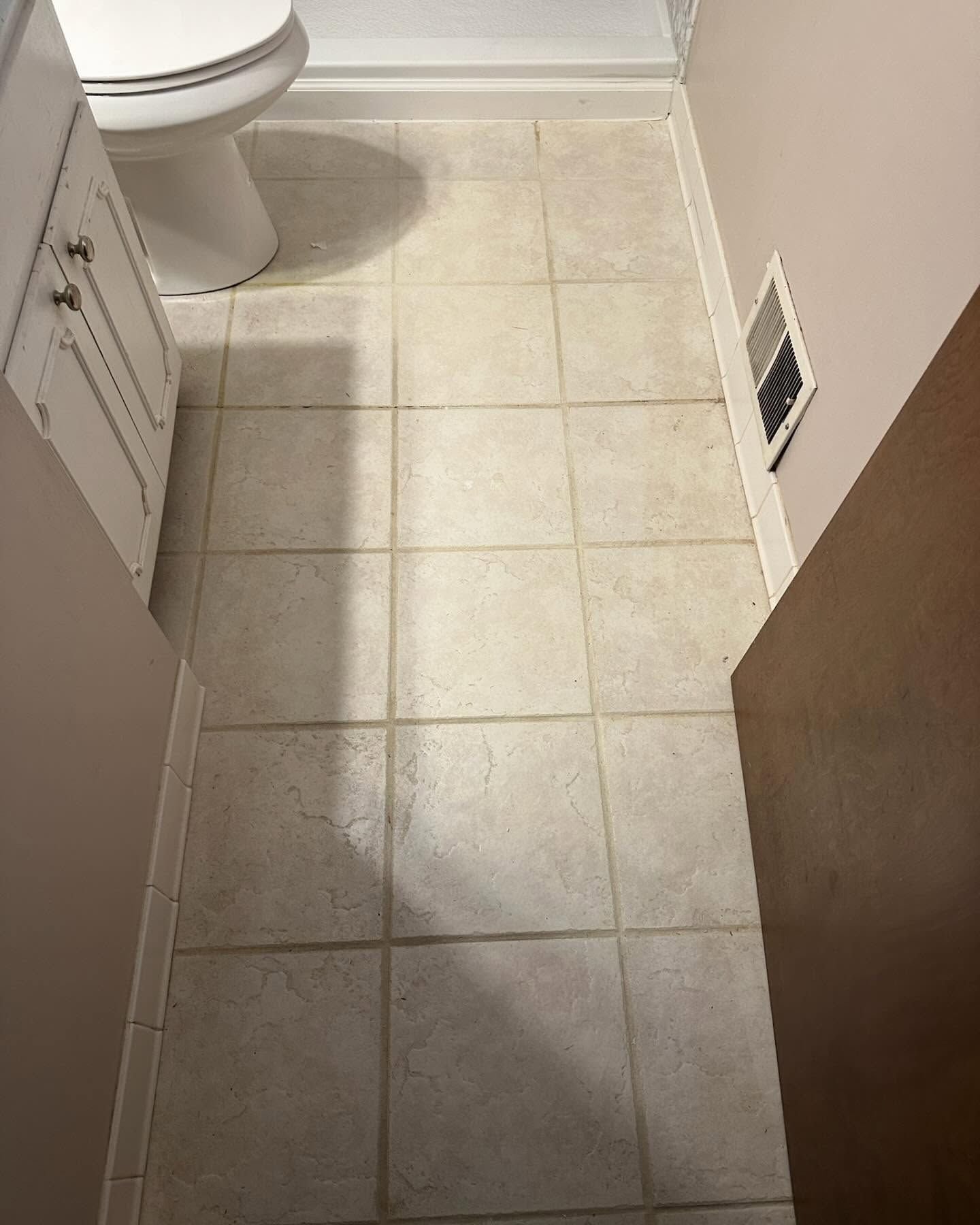 Small tiled bathroom floor with toilet, vanity edge, and wall vent Small tiled bathroom floor with toilet, vanity edge, and wall vent