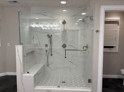 Modern bathroom with glass-enclosed marble shower, bench, and patterned tile floor Modern bathroom with glass-enclosed marble shower, bench, and patterned tile floor