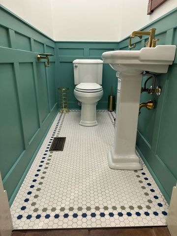 Small teal bathroom with toilet, pedestal sink, and white hex tile floor. Small teal bathroom with toilet, pedestal sink, and white hex tile floor.