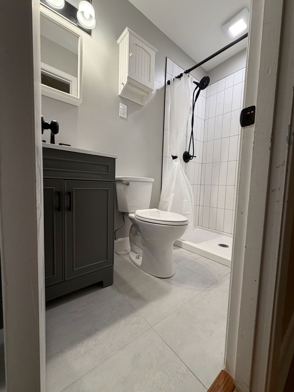Small bathroom with vanity, toilet, and shower in gray and white tones. Small bathroom with vanity, toilet, and shower in gray and white tones.