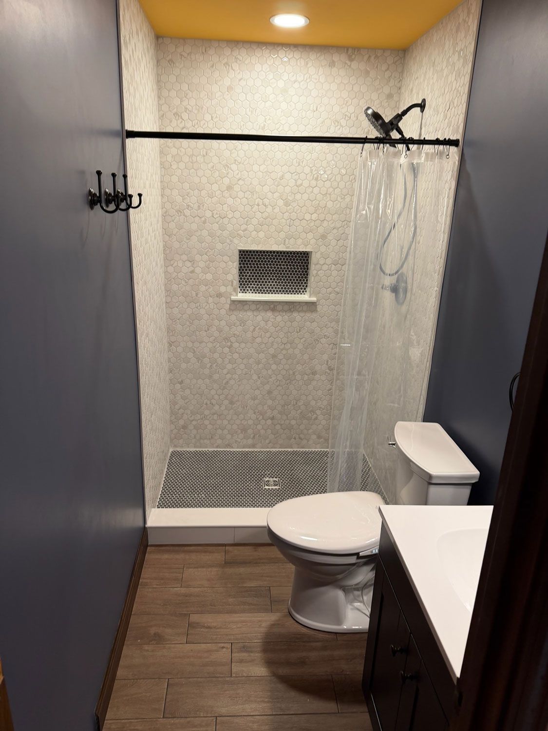 Small modern bathroom with toilet, sink, shower, and gray textured walls. Small modern bathroom with toilet, sink, shower, and gray textured walls.