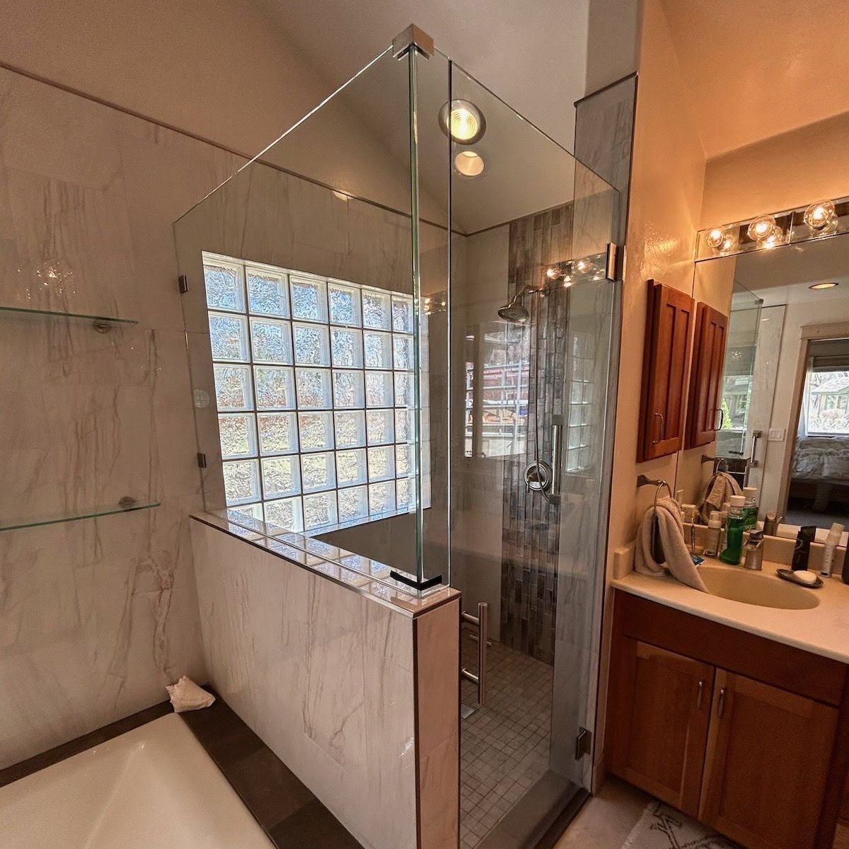 Bathroom with a glass shower enclosure, marble walls, and wooden vanity.