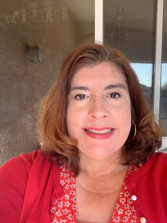 Smiling woman with shoulder-length brown hair, wearing a red floral dress and cardigan.