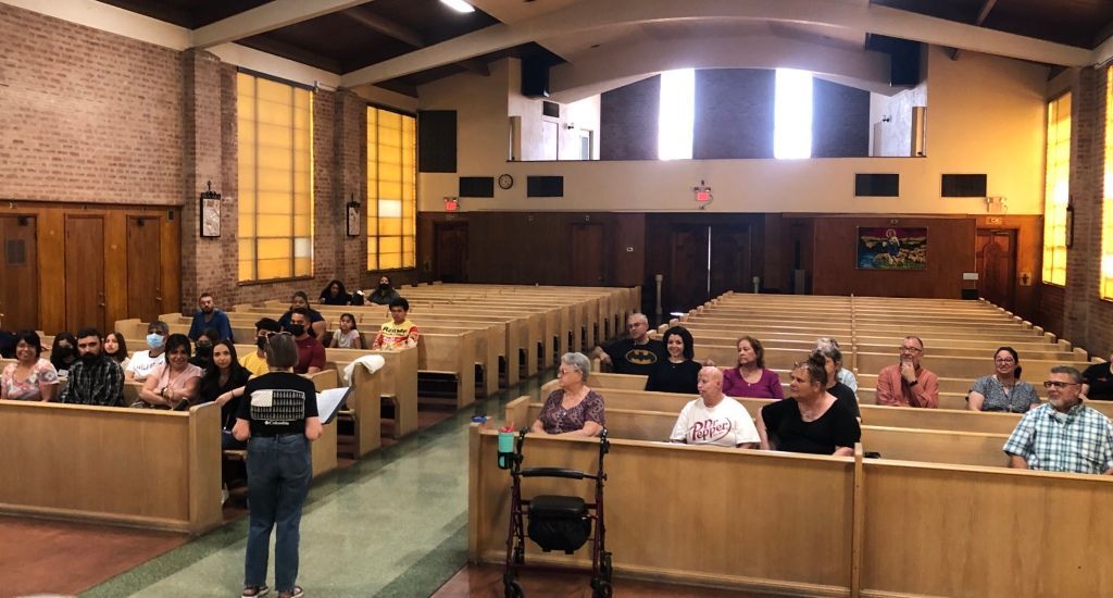 A group of people sit in wooden pews within a church.