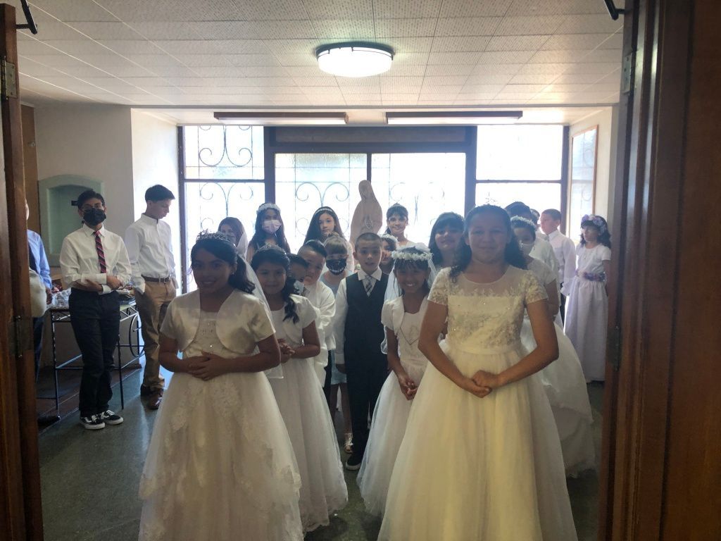 A group of children, dressed in white dresses and suits.