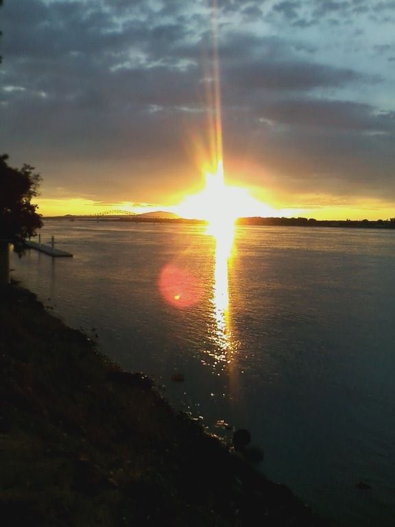 Sunset over a calm river with a glowing reflection on the water. 