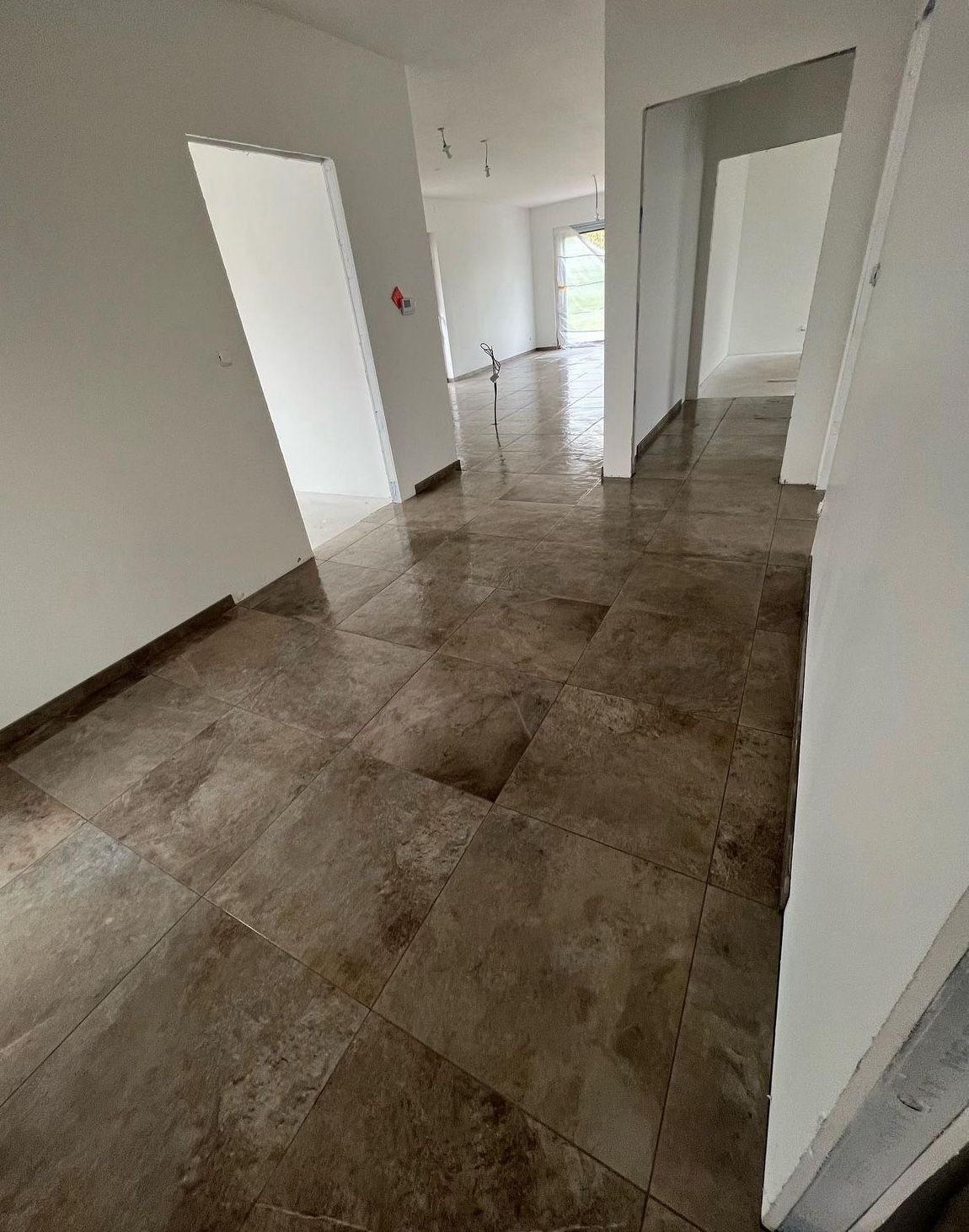 Une grande pièce vide avec un sol carrelé et des murs blancs.