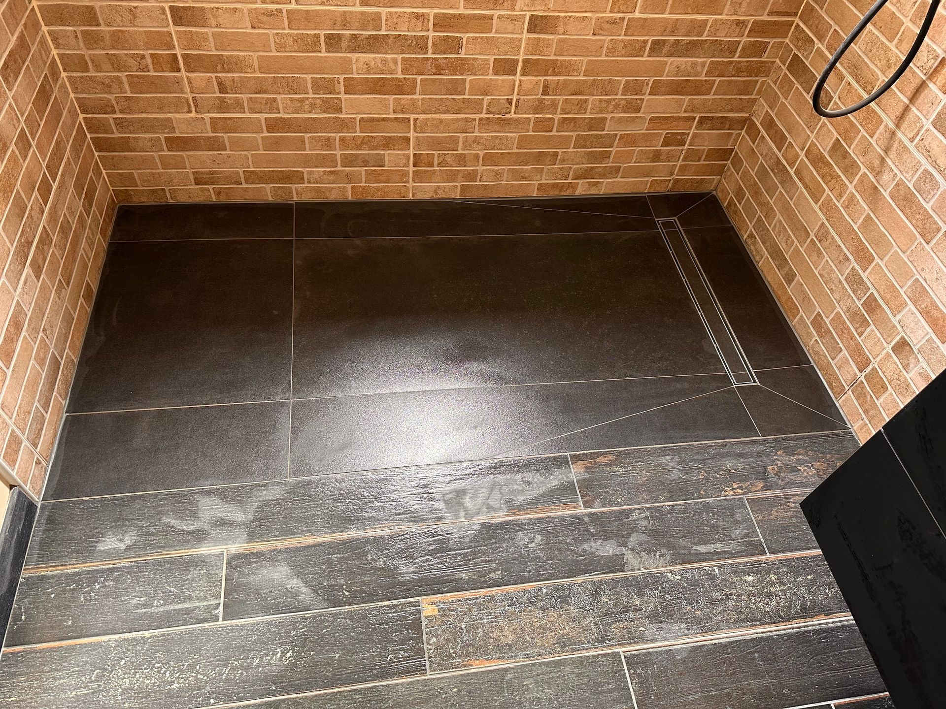 Une salle de bain avec un mur en briques et un sol en carrelage noir.
