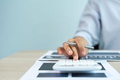 Hand using calculator on financial charts at a desk