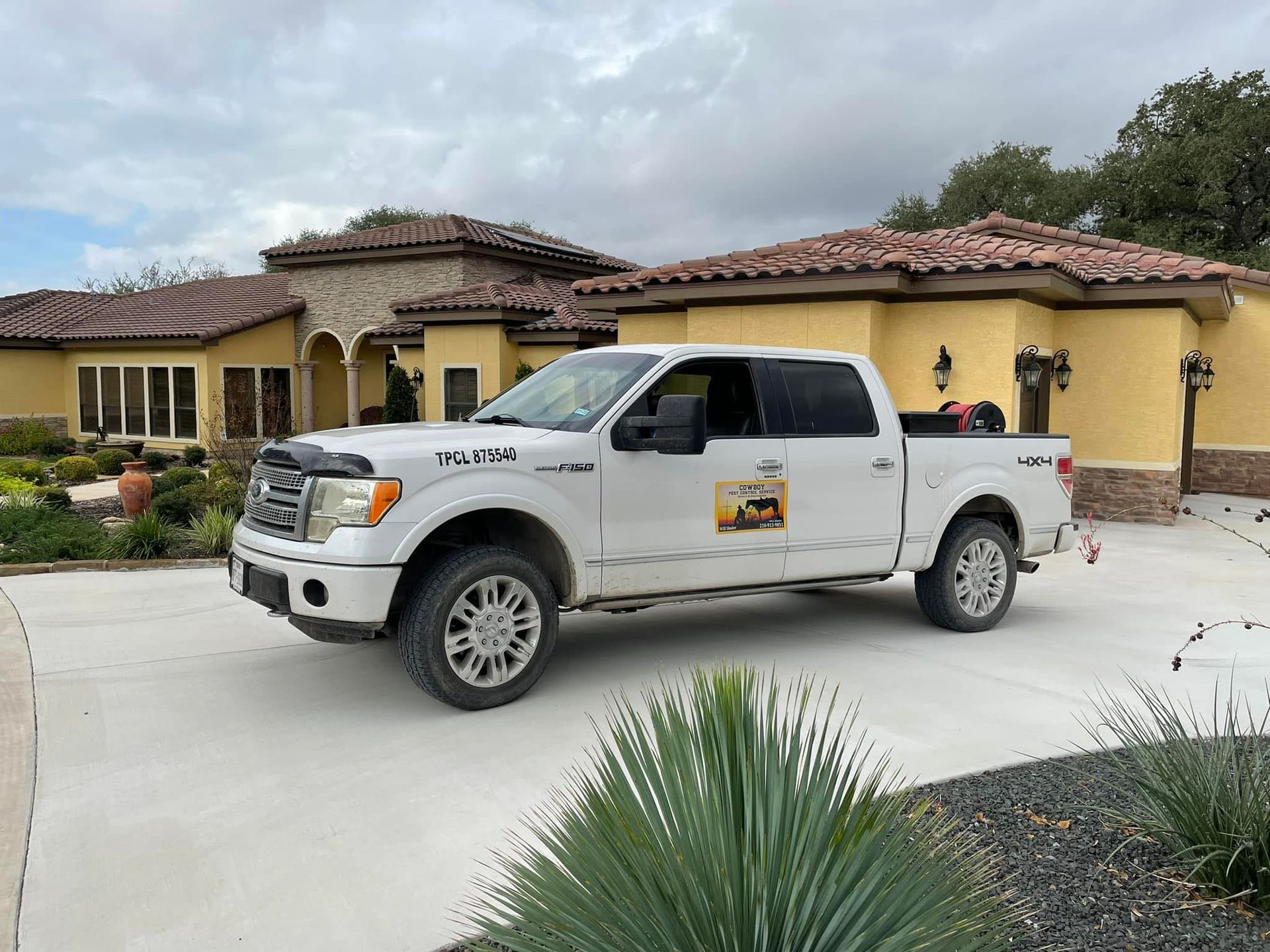A white truck is parked in front of a large house.