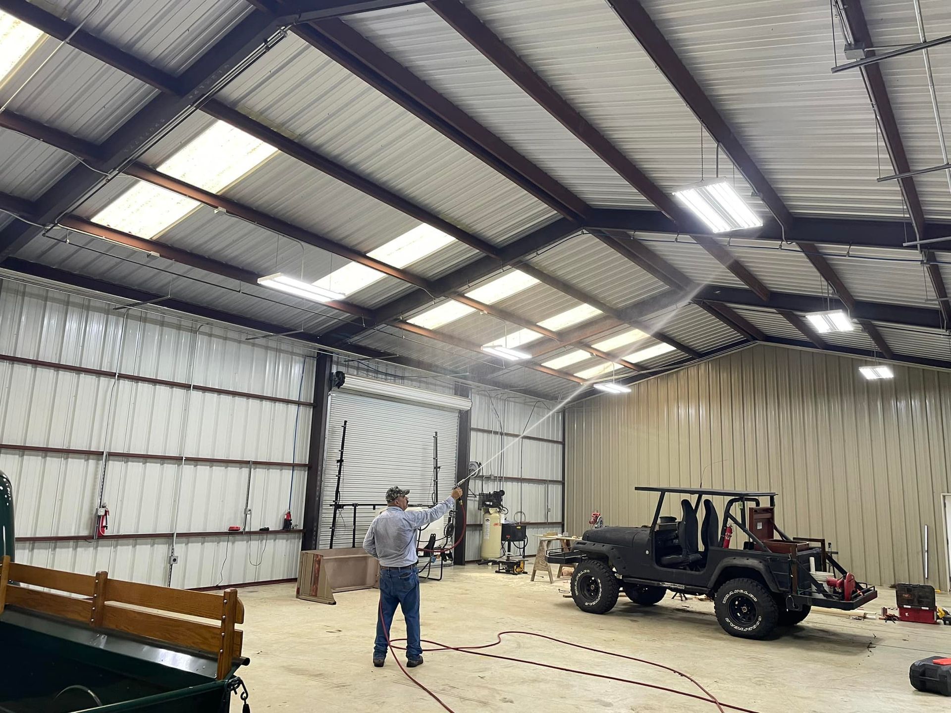 A man is spraying a jeep in a garage.