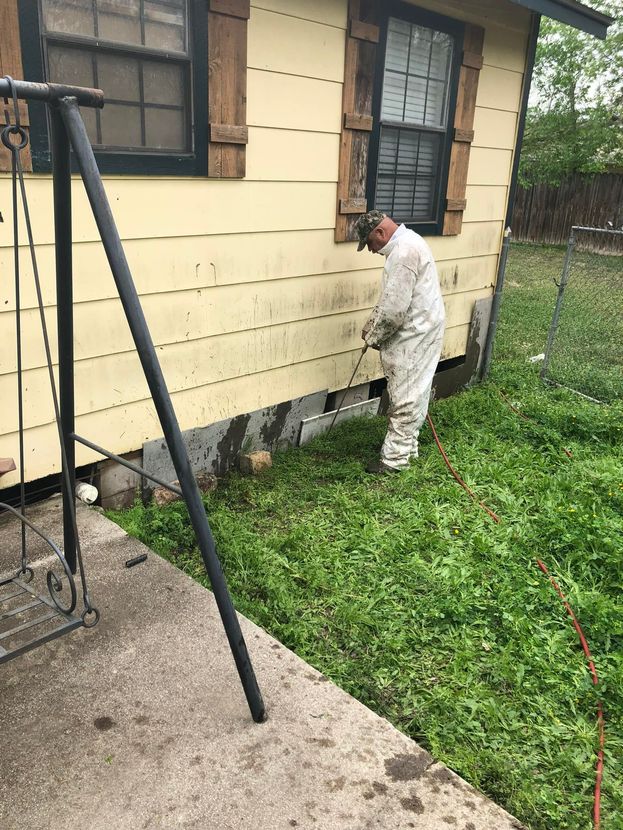 A man in a bee suit is standing in front of a house.