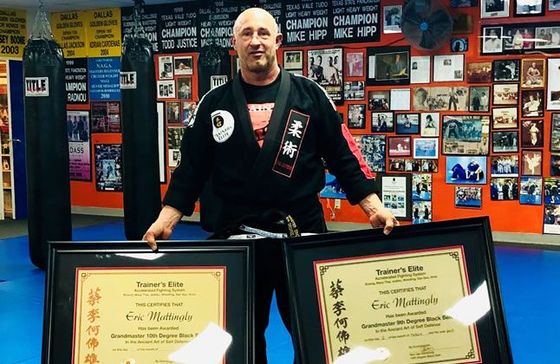 A man is holding two framed certificates in a gym