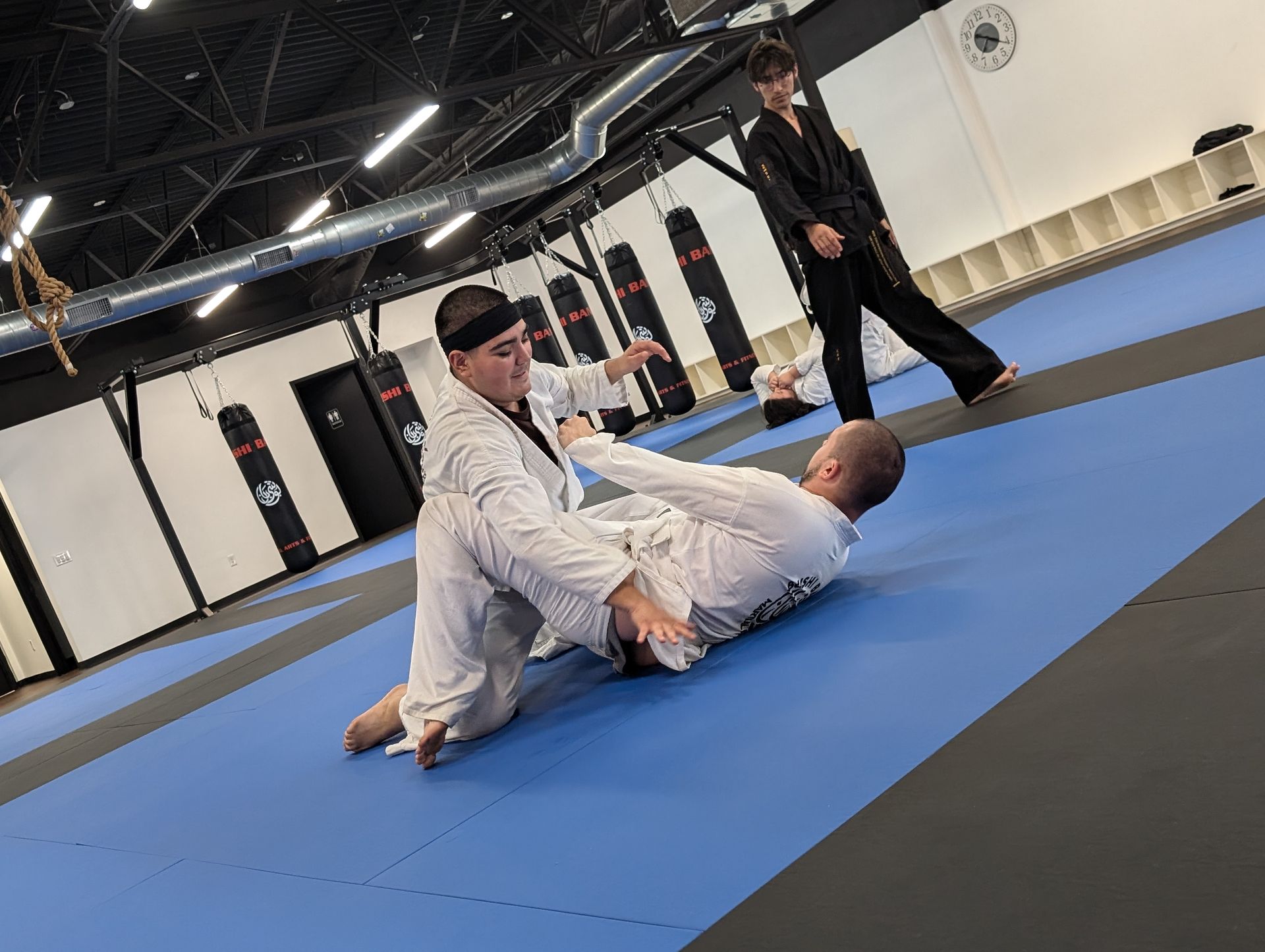 Two men are wrestling on a mat in a gym.