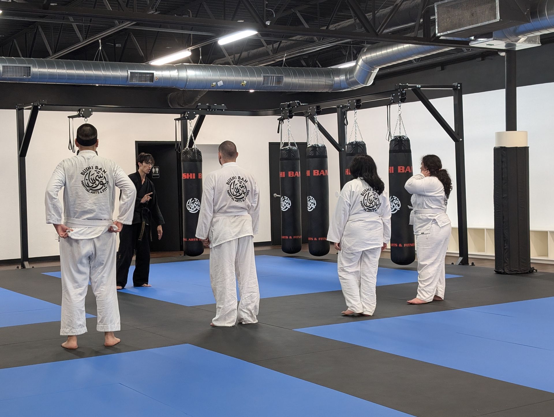 A group of people in karate uniforms are standing in a gym.