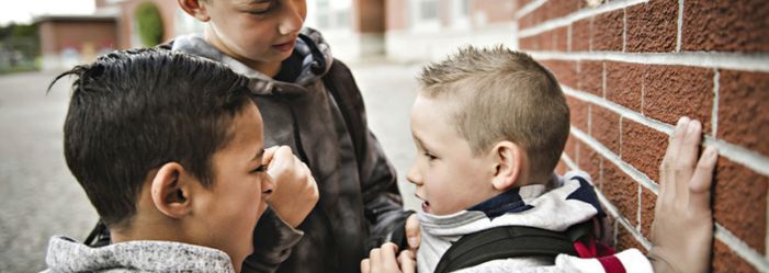 Adolescent boys intimidating a young boy at school