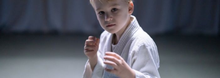 6 year old boy posing in his karate uniform