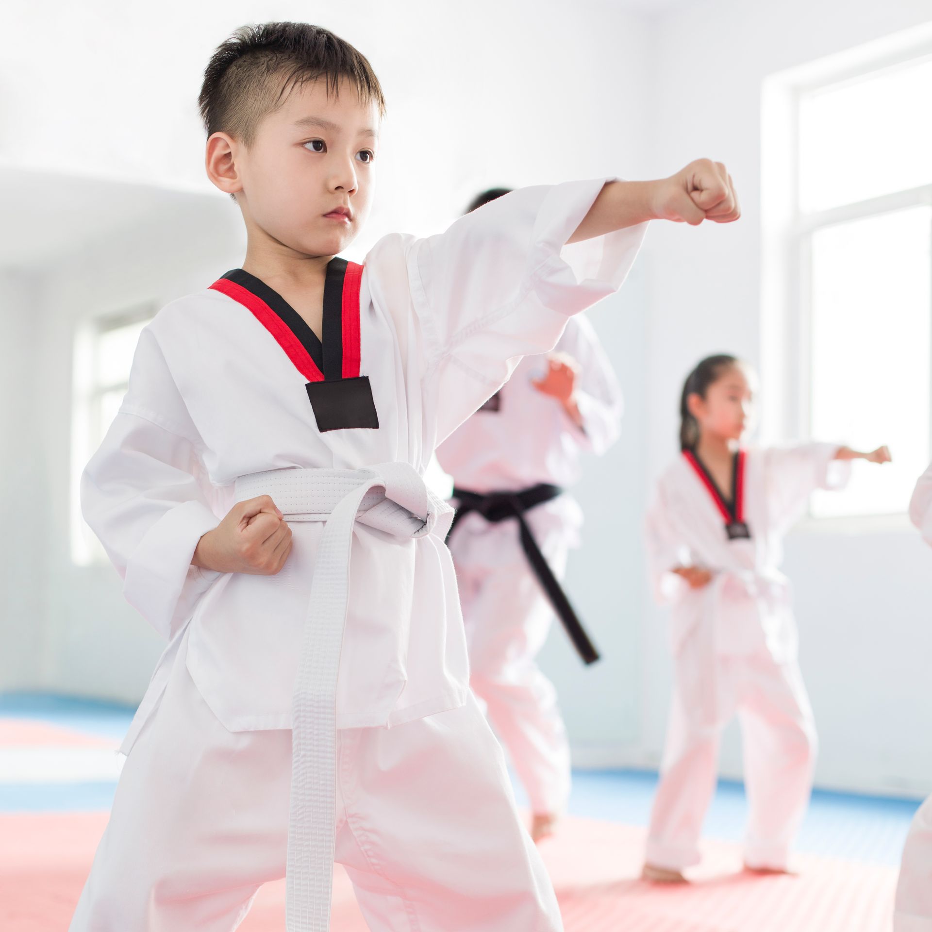 A group of children are practicing karate in a gym.