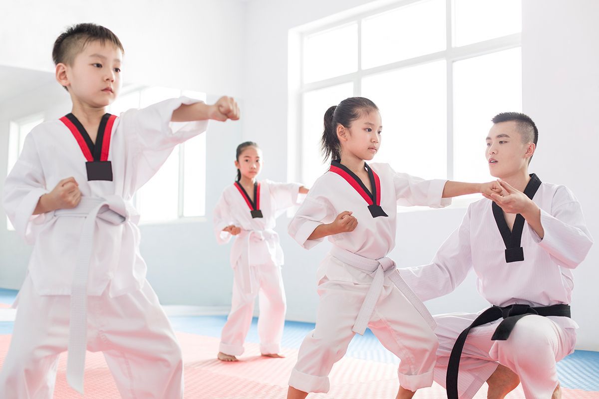 A group of children are practicing taekwondo in a gym.