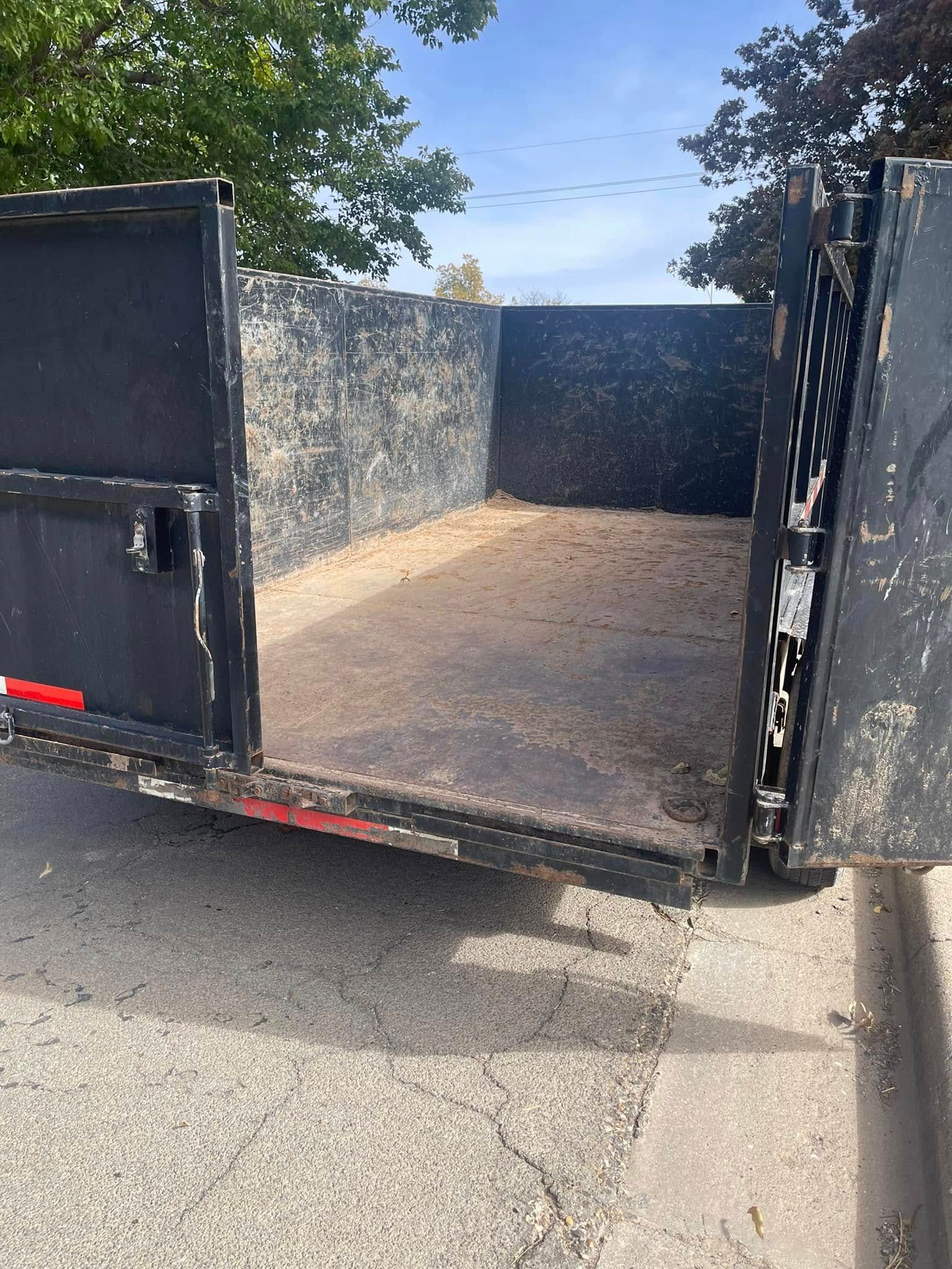 A dumpster is parked on the side of the road with the door open.